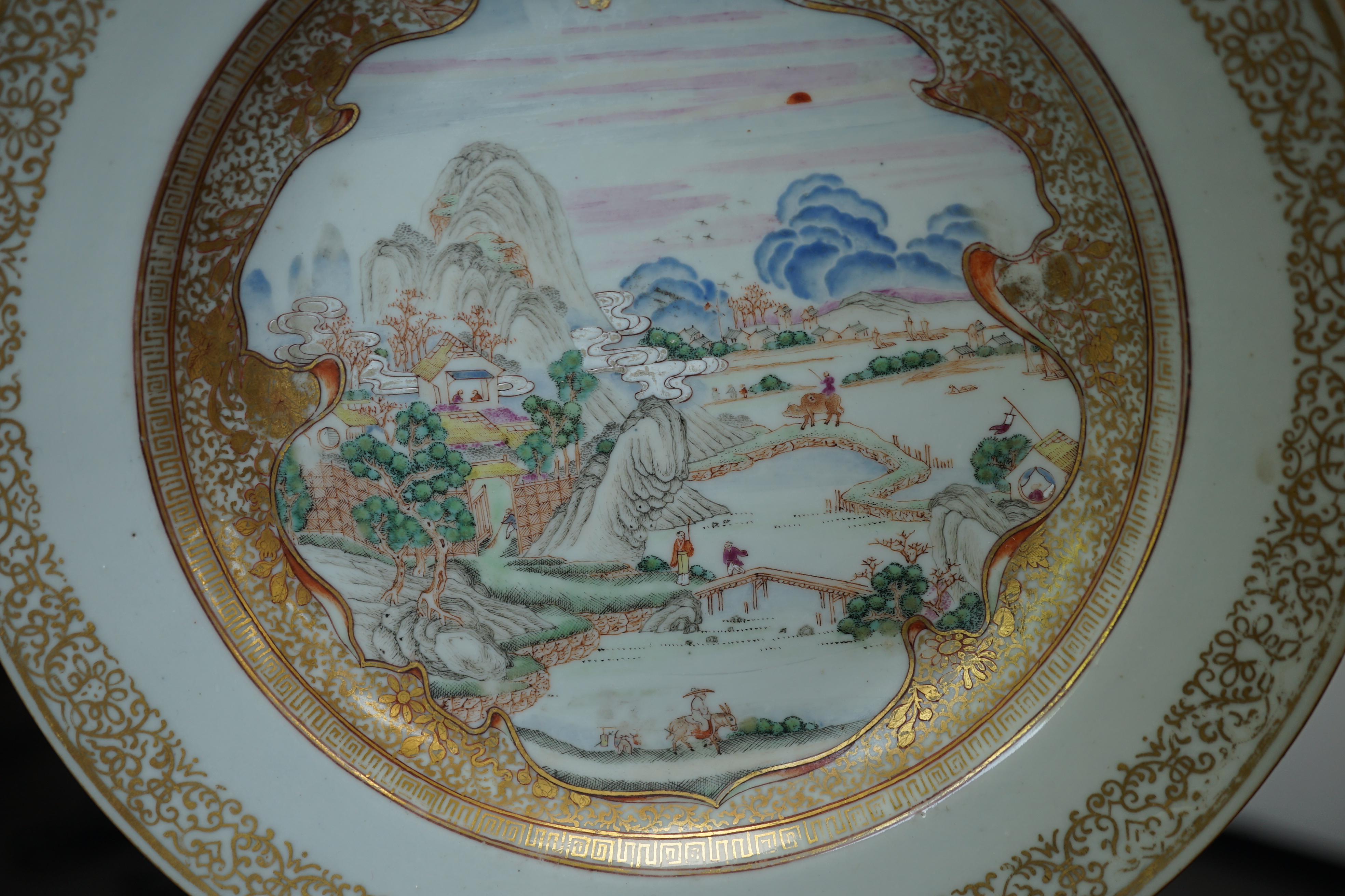 A pair of Chinese famille rose ‘landscape’ plates, Yongzheng-Qianlong period, small edge chip